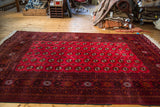 Distinct cranberry red gul motifs and dark patterned border on a vintage Bokhara rug.