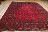 Bokhara rug's cherry red field with geometric gul patterns and dark decorative border.