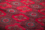 Visible cherry red field and intricate gul motifs on the Bokhara rug's dense wool pile.