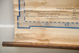 Vintage map's bottom edge, showing blue border, discolored paper, and a wood dowel.