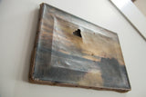 Side angle view of the antique Moor painting showing its weathered canvas and central tear.
