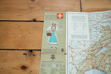 Cover illustration of a woman on a vintage map of Switzerland, shown partially open.