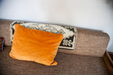Velvety orange pillow with cream and black geometric motif from an antique rug fragment.