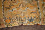 Close-up of antique orange Caucasian pillow's hand-knotted geometric weave in yellow, black, and blue.