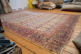 Distressed antique Persian Kerman carpet with cypress trees and dark navy border.