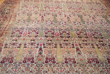 Stylized cypress tree motifs and intricate floral details on the distressed antique Persian Kerman rug.