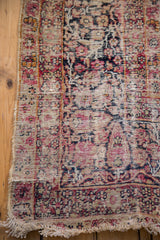 Distressed pile, faded cypress tree patterns, and fringe on antique Kerman carpet.