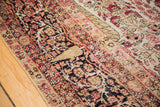 Intricate red, dark blue, and beige distressed motifs and restorative weaving on antique Kerman rug.