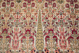 Detail of antique Persian Kerman carpet, cream background with red floral and cypress tree motif.