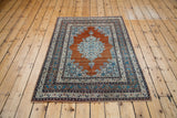 Antique Haji Jalili Tabriz rug displaying its rust and aqua palette from an angled view.