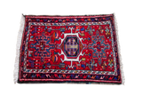 Vintage Persian Karaja mat with central geometric medallion, red field, and blue tribal patterns.