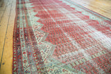 Faded red, ivory, and blue-green Mir-boteh patterns on distressed antique Malayer rug.