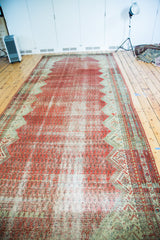 Distressed raspberry cinnabar red field with Mir-boteh patterns and geometric blue-green border.