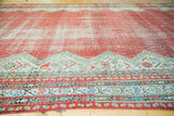 Distressed raspberry red field and geometric ivory, blue-green border of antique Malayer rug.