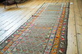 Distressed pile and geometric border patterns on this early 20th century Caucasian runner.