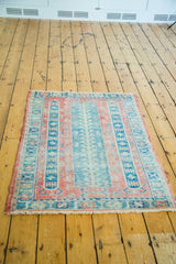 Distressed vintage Turkish Sparta rug corner with fringed edge, raspberry, seafoam, and aqua tones.