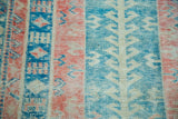 Distressed vintage Turkish rug with striped geometric patterns in raspberry red, seafoam green, and aqua.