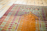 Distressed burnt orange prayer field with geometric patterns on a Kula rug.