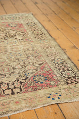Detailed corner of an antique Persian Sarouk rug with raspberry, charcoal, and light blue floral patterns.