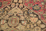 Intricate floral motifs in charcoal, raspberry, and powder blue on an antique Farahan Sarouk rug pile.