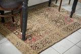 Styled in-situ view of an antique Persian Farahan Sarouk rug with a time-softened palette.