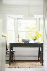 Antique Persian Farahan Sarouk rug grounding a vintage table in a sunlit, whitewashed room.