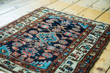 Detail of the vintage Hamadan rug's small center medallion and Herati field in coral and blue.