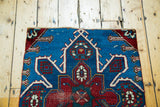 Expressive blue and red geometric medallion with unique asymmetrical details on rug fragment.