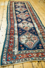 Distressed navy field and geometric motifs of an antique Caucasian runner.