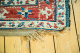 Antique Caucasian runner's distressed corner, showing red, blue geometric motifs and worn fringe.
