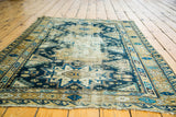 Distressed antique Caucasian Shirvan rug showing worn geometric blue and gold patterns.