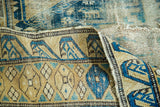 Detail of folded antique Shirvan rug, showing fine weave and distressed blue geometric patterns.