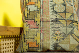 Detail of the antique Caucasian fragment pillow showing hand-knotted geometric orange and yellow.