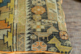 Textured hand-knotted geometric pattern in orange, yellow, and black on the antique pillow.