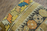 Textured antique Caucasian fragment pillow with orange, yellow, and blue geometric motifs.