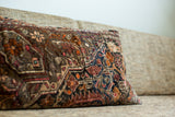 Intricate dark blue, rust, and brown floral pattern on a vintage Sarouk style rug pillow.