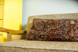 Vintage Sarouk style pillow close-up with intricate dark blue and earth tone floral patterns.