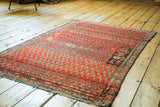 Distressed brick red field with repeating boteh motifs and unique charcoal cartouche.