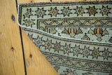 Antique Caucasian rug corner showing distressed pile, star border, and hand-knotted foundation.