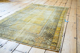 Distressed gold field, Ladik style patterns, and secured side of a vintage Turkish prayer rug.