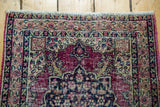 Distressed red pile and intricate blossoming floral patterns on an antique Persian Kerman rug.
