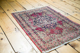 Antique Kerman rug corner, showing distressed floral border and time-softened tones.