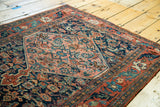 Antique Persian Bijar rug with coral herati medallion and contrasting navy Morris style border.