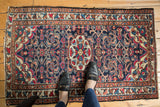 Vintage Lilihan rug's central floral medallion, varied bouquets, and meandering leaf border on dark blue.