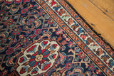 Vintage Lilihan rug's dark blue field with vibrant floral designs and decorative peach border.