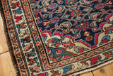 Vintage Lilihan rug corner with its meandering leaf border and dark blue floral field.