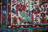 Vintage Hamadan rug corner showing red, blue floral motifs on ivory field with light blue border.