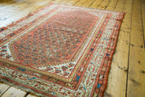 Distressed rust field with traditional allover pattern and fine cream and blue border motifs.