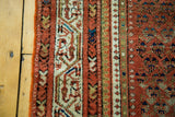 Antique Persian Serbend rug border and rust field with repeating motifs, showing distressed texture.