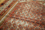 Textured distressed pile of antique Serbend rug with repeating blue and rust patterns.